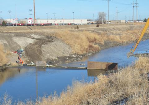 Upstream view of the 14th Street Weir. Lincoln’s Salt Creek Levee Trail and UNL’s Hibner Stadium are in the background.